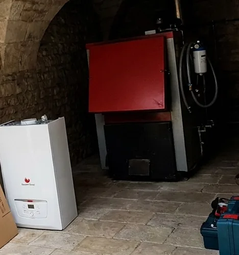 Chaudière gaz murale neuve posée au sol avant installation dans une chaufferie voûtée de Senlis